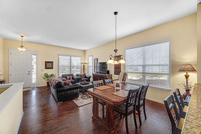 dining area with dark hardwood / wood-style floors, a wealth of natural light, and a chandelier