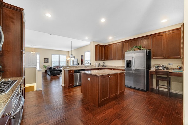 kitchen featuring kitchen peninsula, appliances with stainless steel finishes, light stone countertops, and pendant lighting