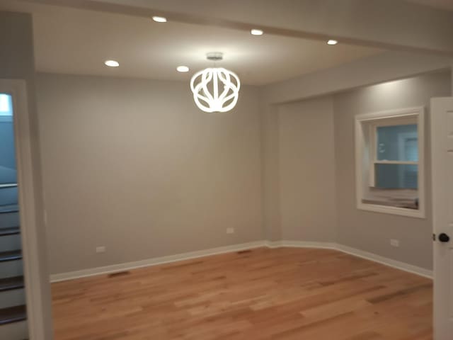 spare room with light hardwood / wood-style floors and a chandelier