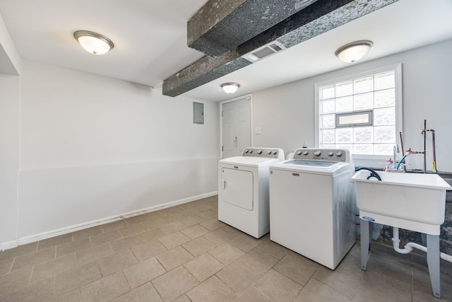 clothes washing area with electric panel, sink, and washer and dryer