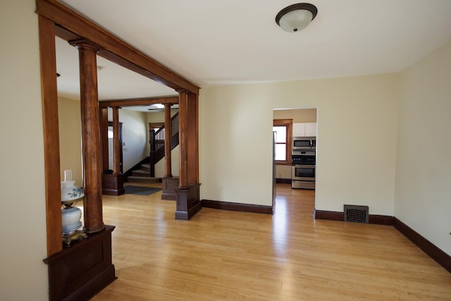 spare room featuring ornate columns and light hardwood / wood-style flooring