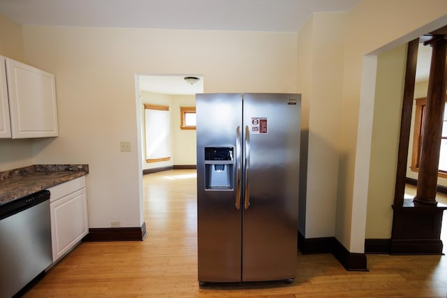 kitchen featuring light hardwood / wood-style floors, white cabinetry, appliances with stainless steel finishes, and dark stone countertops