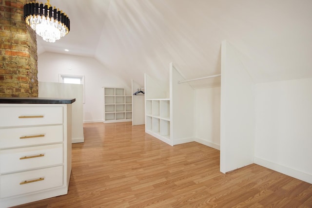 additional living space with light hardwood / wood-style flooring, a chandelier, and vaulted ceiling