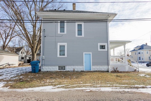 snow covered rear of property featuring a porch