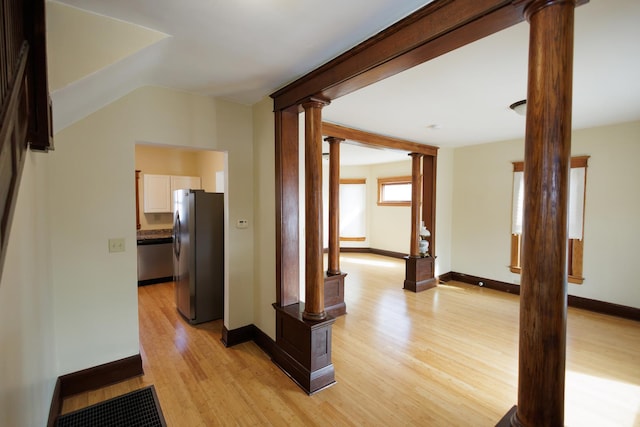 hall with light hardwood / wood-style floors and ornate columns