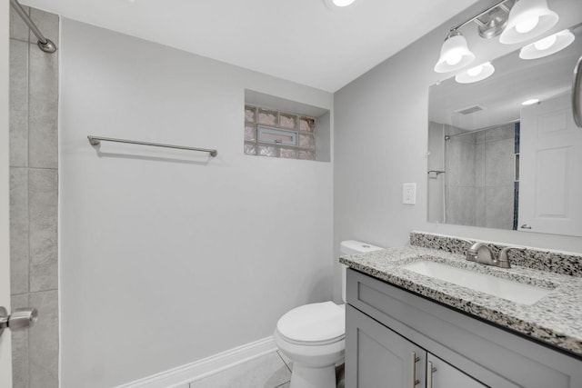 bathroom featuring tile patterned floors, vanity, tiled shower, and toilet