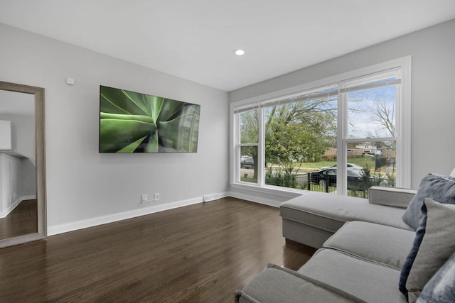 living room with dark wood-type flooring and a healthy amount of sunlight