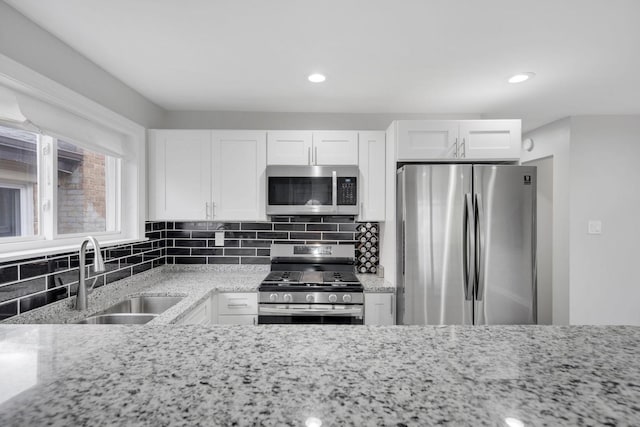 kitchen featuring light stone countertops, appliances with stainless steel finishes, white cabinetry, and sink