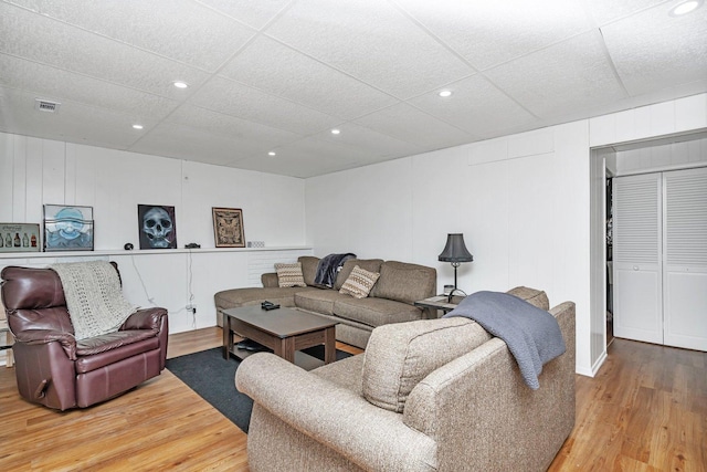 living room featuring a paneled ceiling and hardwood / wood-style flooring