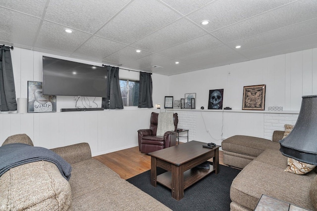 living room featuring a drop ceiling and dark wood-type flooring