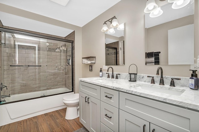 full bathroom featuring vanity, hardwood / wood-style flooring, toilet, and bath / shower combo with glass door