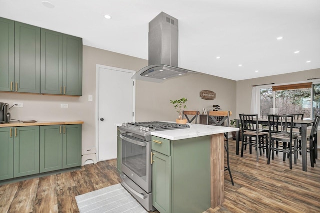 kitchen featuring green cabinets, gas range, dark hardwood / wood-style floors, a kitchen bar, and island exhaust hood