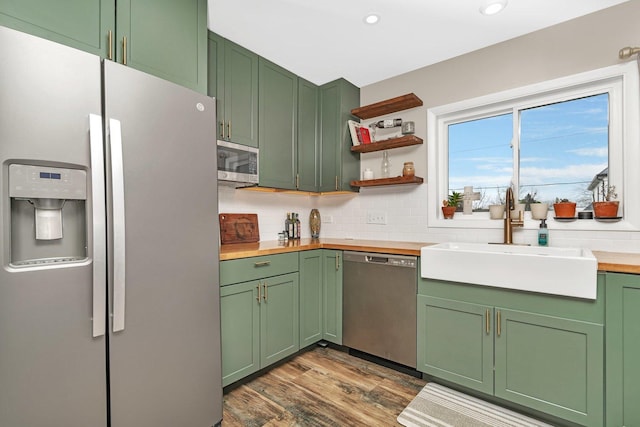 kitchen with dark hardwood / wood-style flooring, stainless steel appliances, sink, green cabinetry, and butcher block countertops