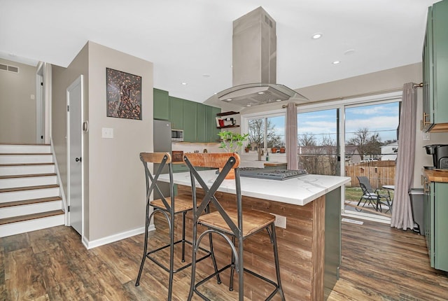 kitchen featuring dark hardwood / wood-style flooring, stainless steel appliances, island exhaust hood, and green cabinetry