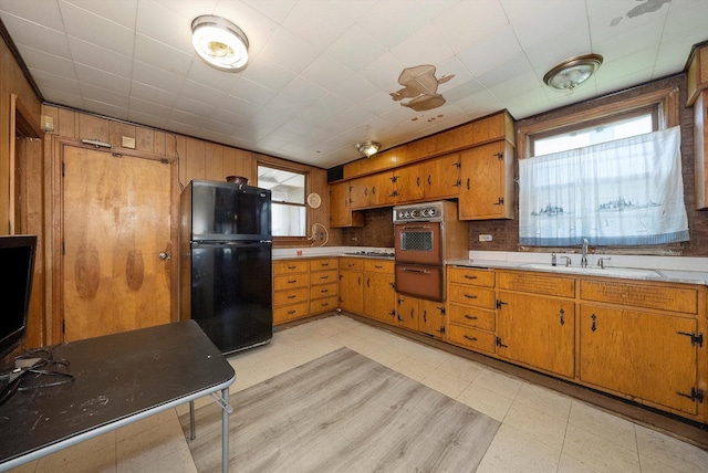 kitchen with oven, a healthy amount of sunlight, black fridge, and sink