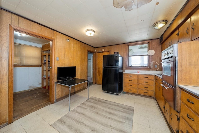 kitchen featuring black refrigerator and wooden walls