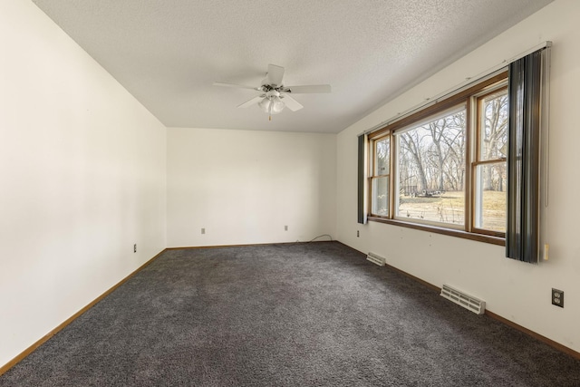 spare room with dark colored carpet, a textured ceiling, and ceiling fan