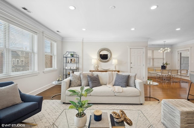 living room with a chandelier, light hardwood / wood-style floors, and ornamental molding