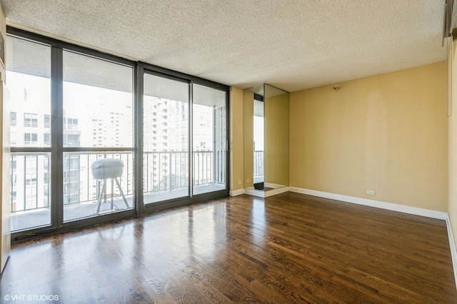 spare room featuring dark wood-type flooring, floor to ceiling windows, and a textured ceiling