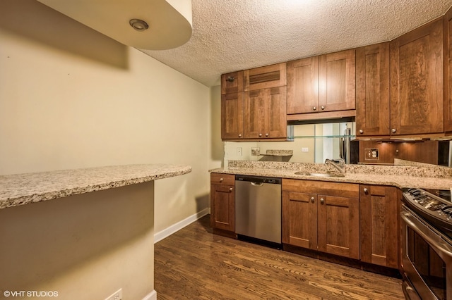 kitchen with sink, light stone counters, a textured ceiling, appliances with stainless steel finishes, and dark hardwood / wood-style floors