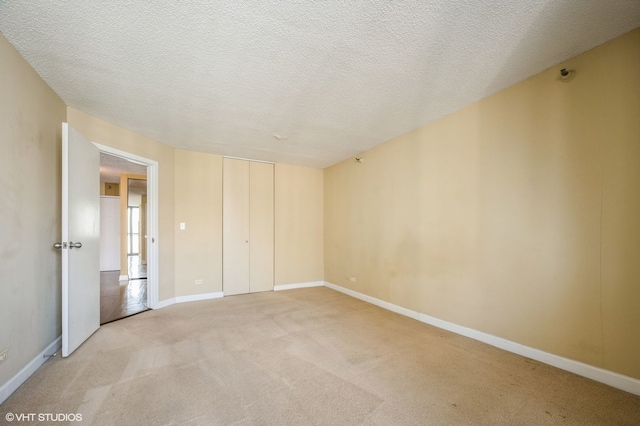 unfurnished bedroom featuring light colored carpet, a textured ceiling, and a closet