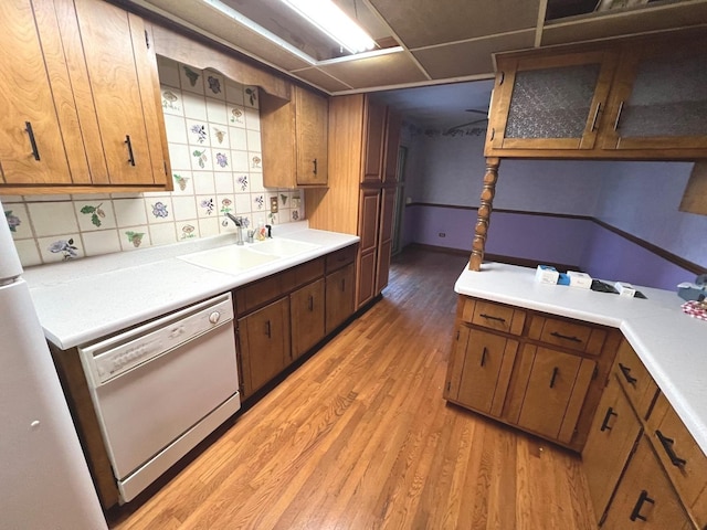 kitchen with decorative backsplash, dishwasher, light wood-type flooring, and sink