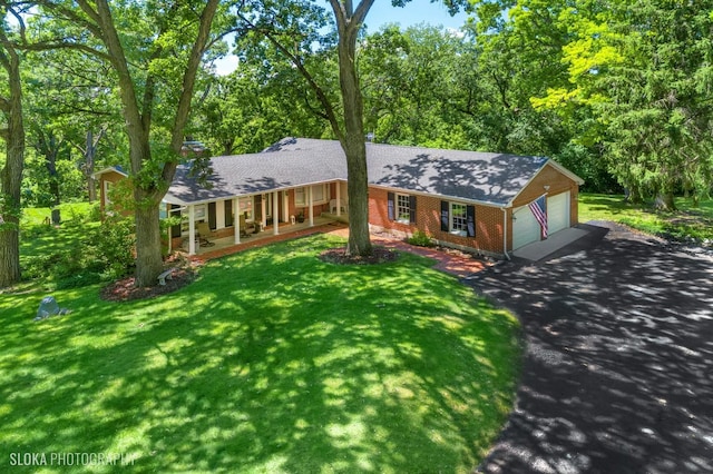 ranch-style home featuring covered porch, a garage, and a front yard