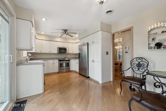 kitchen featuring white cabinets, ceiling fan with notable chandelier, sink, and stainless steel appliances