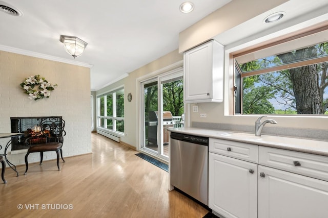 kitchen featuring dishwasher, white cabinets, crown molding, a brick fireplace, and light hardwood / wood-style flooring