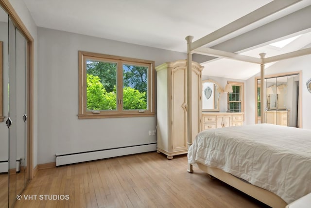 bedroom featuring a skylight, a baseboard heating unit, and light hardwood / wood-style floors