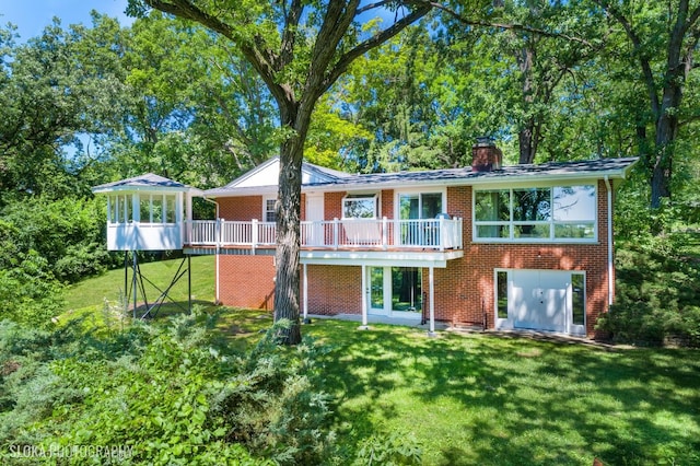 back of house featuring a lawn, a sunroom, and a deck