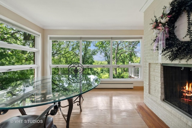 sunroom featuring a fireplace, baseboard heating, and a healthy amount of sunlight