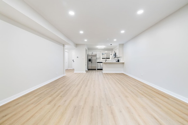 unfurnished living room with light hardwood / wood-style flooring and sink