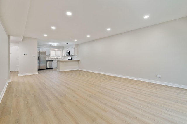 unfurnished living room with sink and light hardwood / wood-style floors