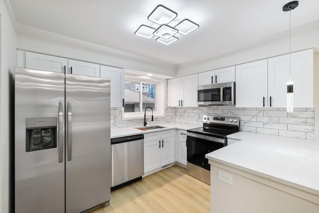 kitchen featuring sink, white cabinets, hanging light fixtures, and appliances with stainless steel finishes