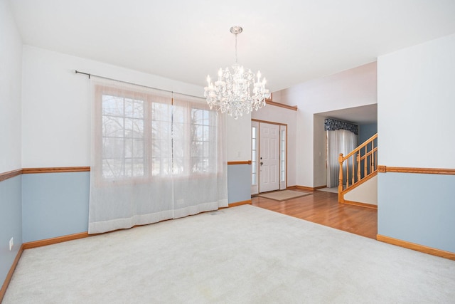 carpeted empty room with an inviting chandelier