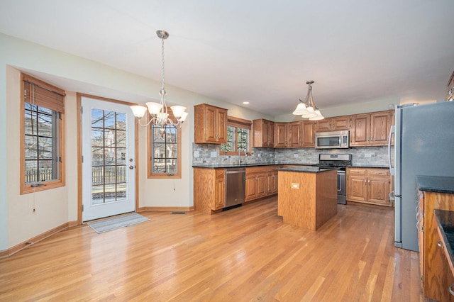 kitchen featuring appliances with stainless steel finishes, sink, pendant lighting, a notable chandelier, and a kitchen island