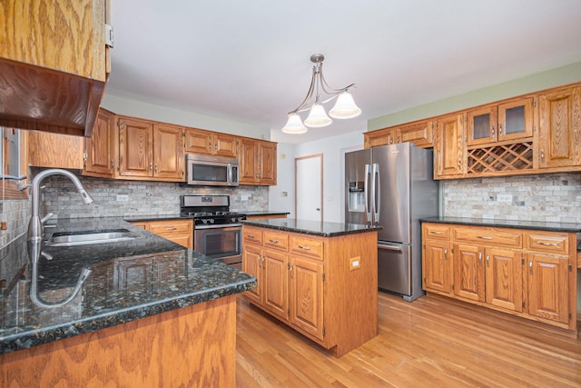 kitchen with a center island, sink, hanging light fixtures, tasteful backsplash, and stainless steel appliances