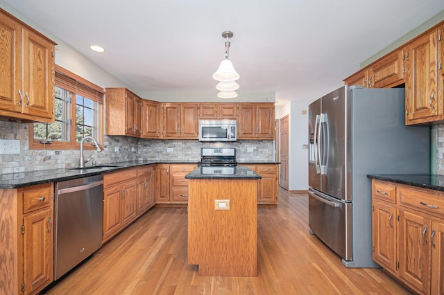 kitchen with a center island, sink, decorative backsplash, light wood-type flooring, and appliances with stainless steel finishes