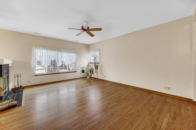 unfurnished living room featuring a brick fireplace, hardwood / wood-style floors, and ceiling fan