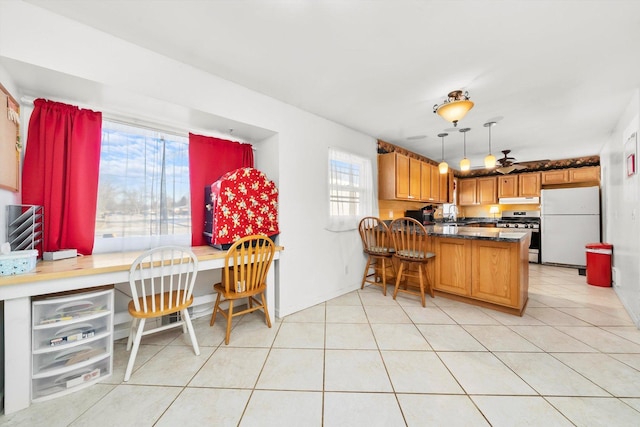 kitchen featuring white fridge, stainless steel stove, hanging light fixtures, kitchen peninsula, and ceiling fan