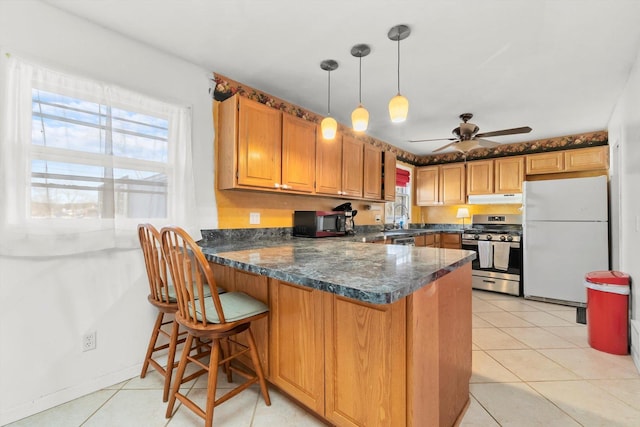 kitchen with pendant lighting, gas stove, white refrigerator, ceiling fan, and light tile patterned floors