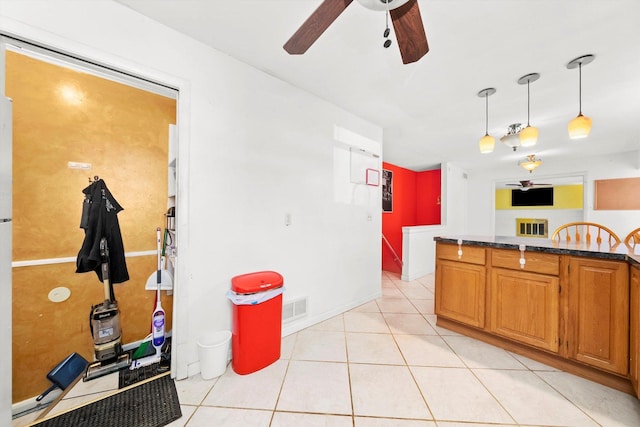 kitchen featuring decorative light fixtures, light tile patterned floors, ceiling fan, and dark stone countertops