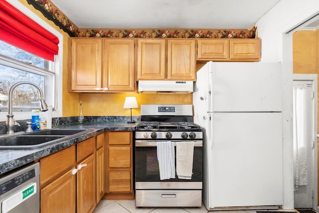 kitchen featuring light tile patterned floors, stainless steel gas range oven, dishwashing machine, white refrigerator, and sink