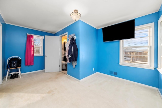 unfurnished bedroom featuring a closet, carpet flooring, crown molding, and connected bathroom