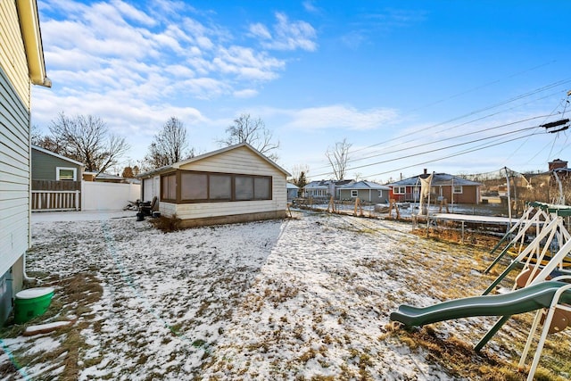 yard covered in snow featuring a trampoline and a playground