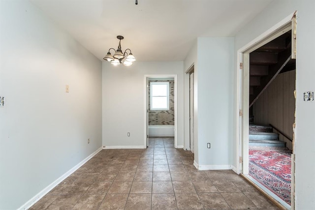 tiled empty room featuring a notable chandelier