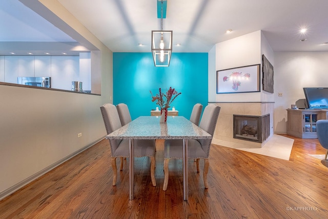 dining room with a tiled fireplace and light hardwood / wood-style flooring