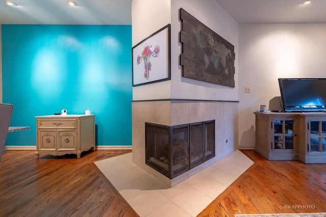 living room with a tiled fireplace and light hardwood / wood-style flooring