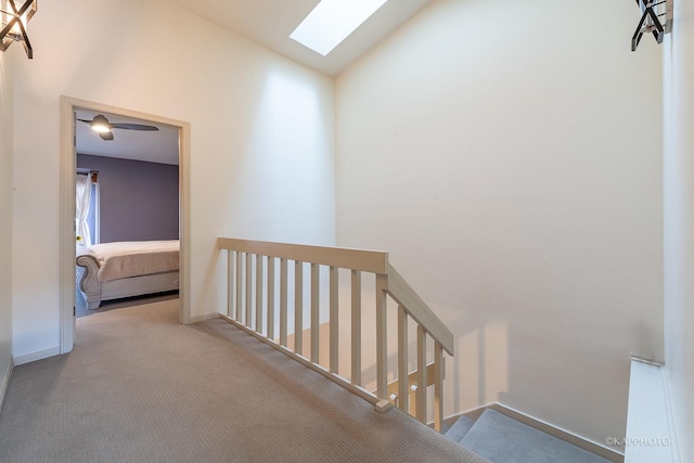 corridor featuring light carpet and vaulted ceiling with skylight